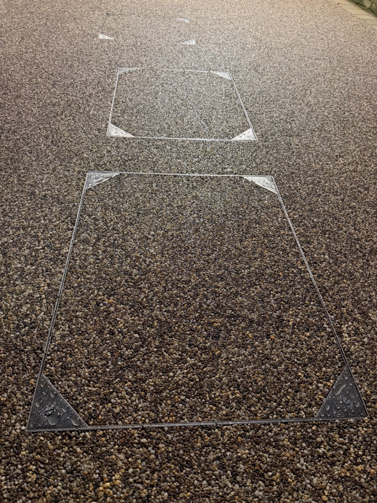 Close detail of the finished resin-bound surface meeting a flush utility cover