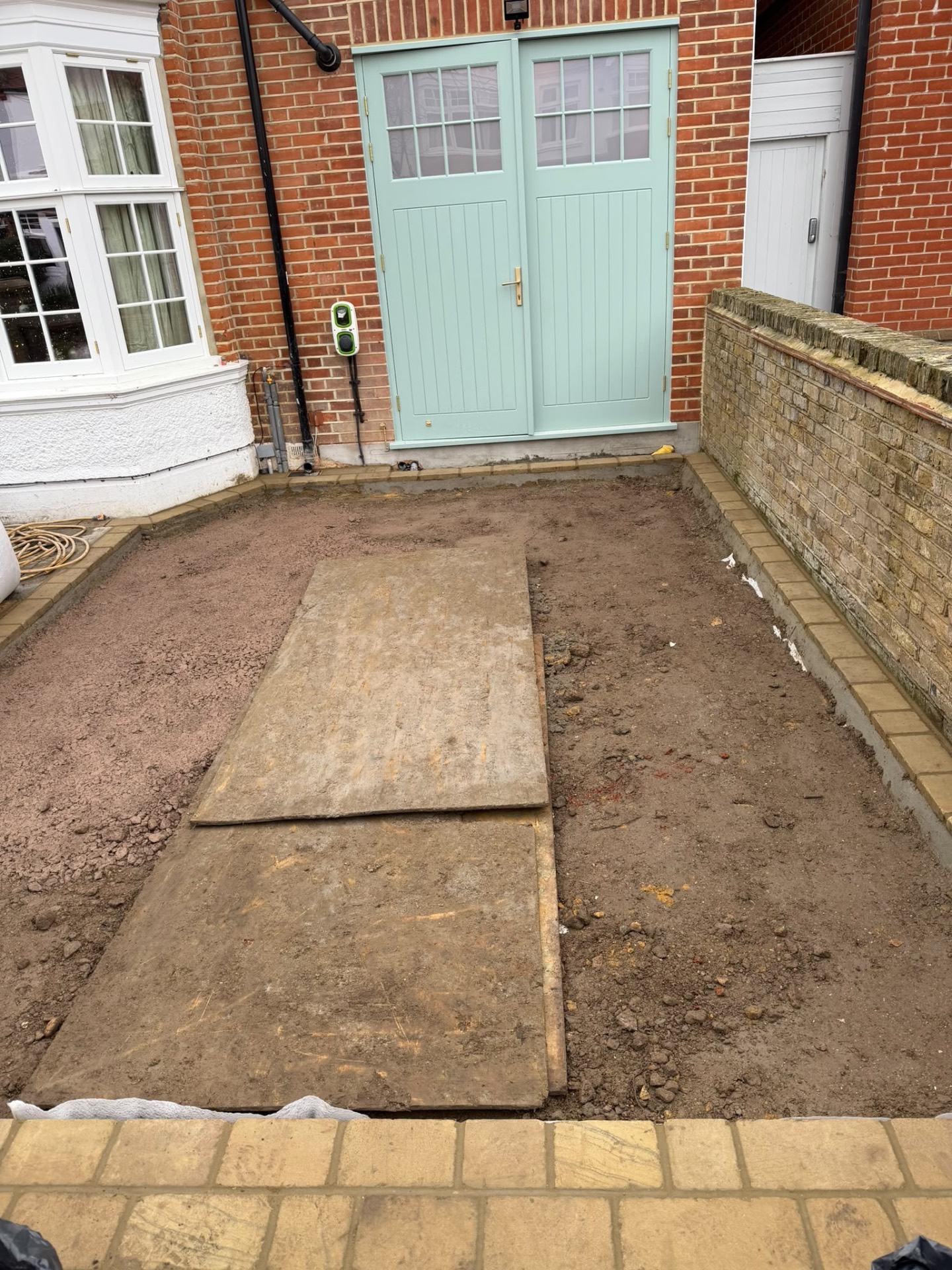 Ground prepared and bordered with stone edging ahead of paving, with a temporary walkway in place