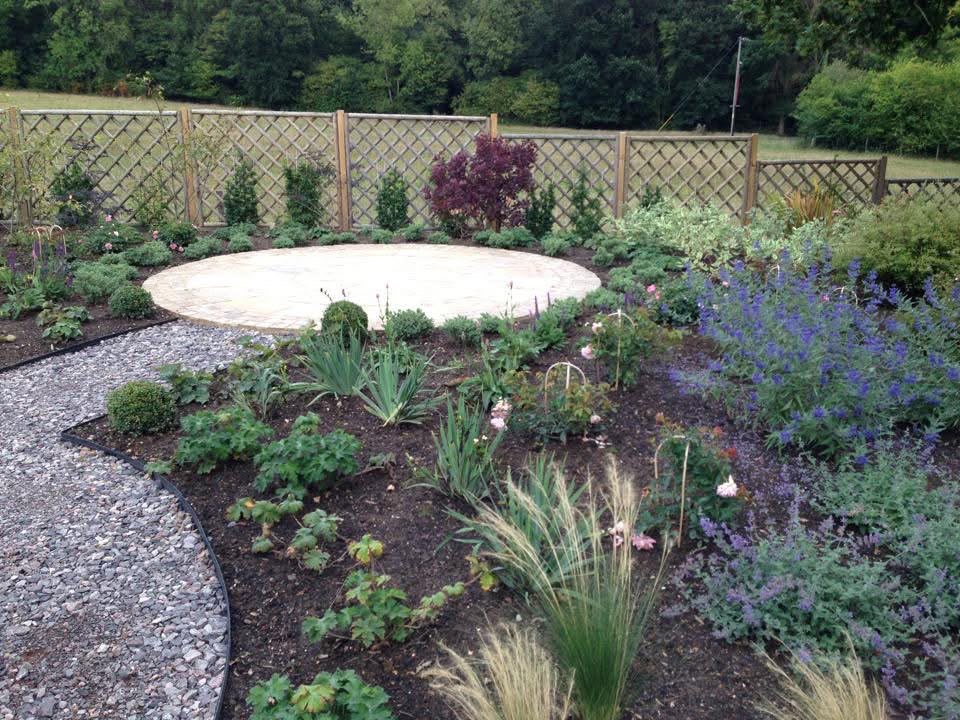 Curved gravel path beside new flower beds and a circular paved area