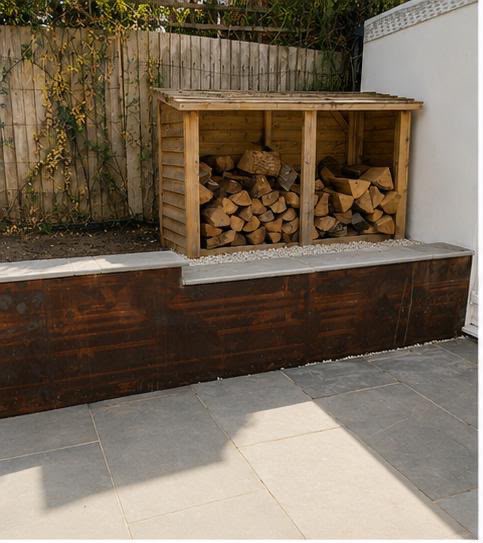 Completed limestone patio with a corten steel retaining wall topped with stone coping and a timber log store above