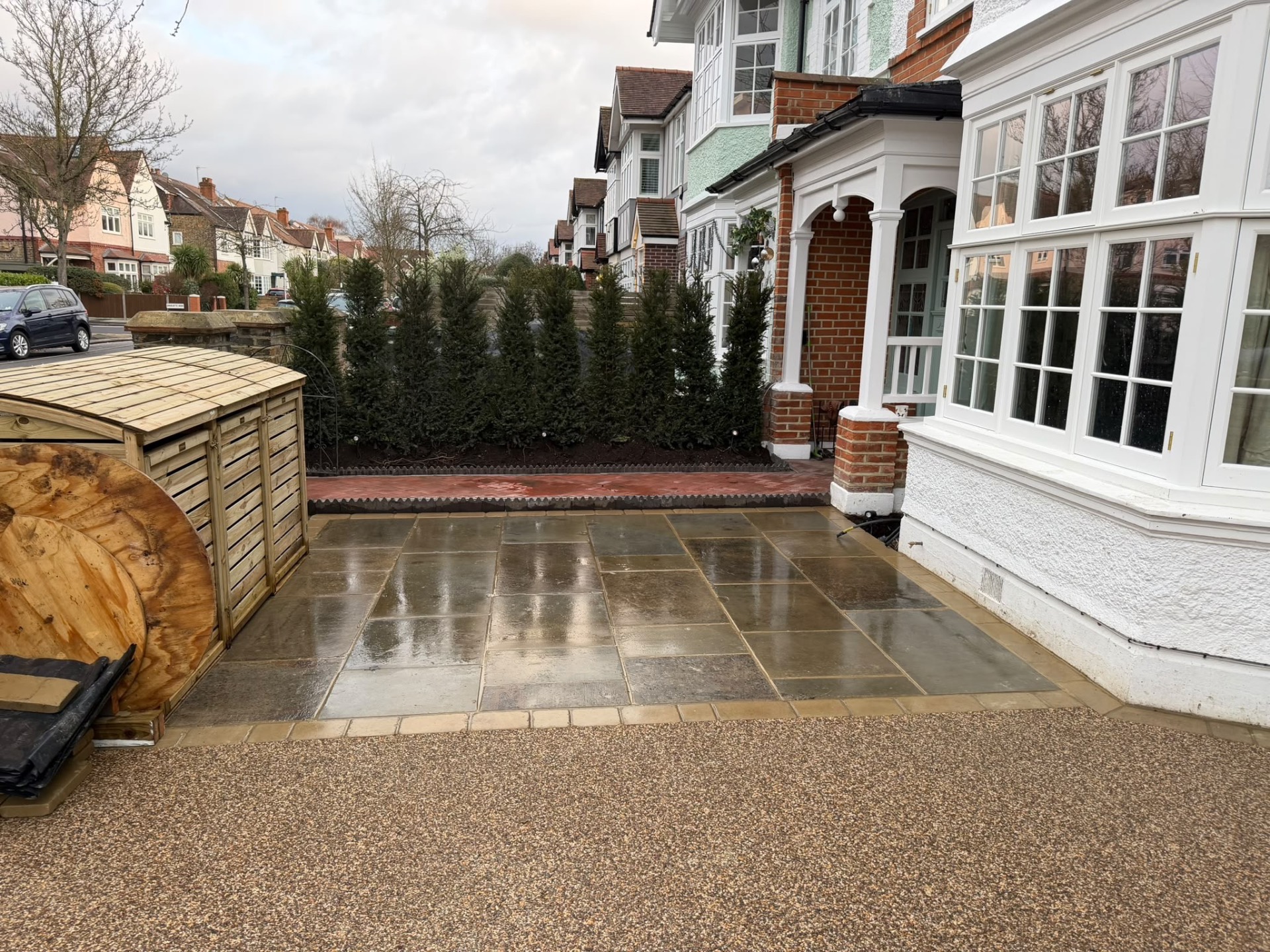 Finished yorkstone paving and resin-bound driveway in front of the house and evergreen screen