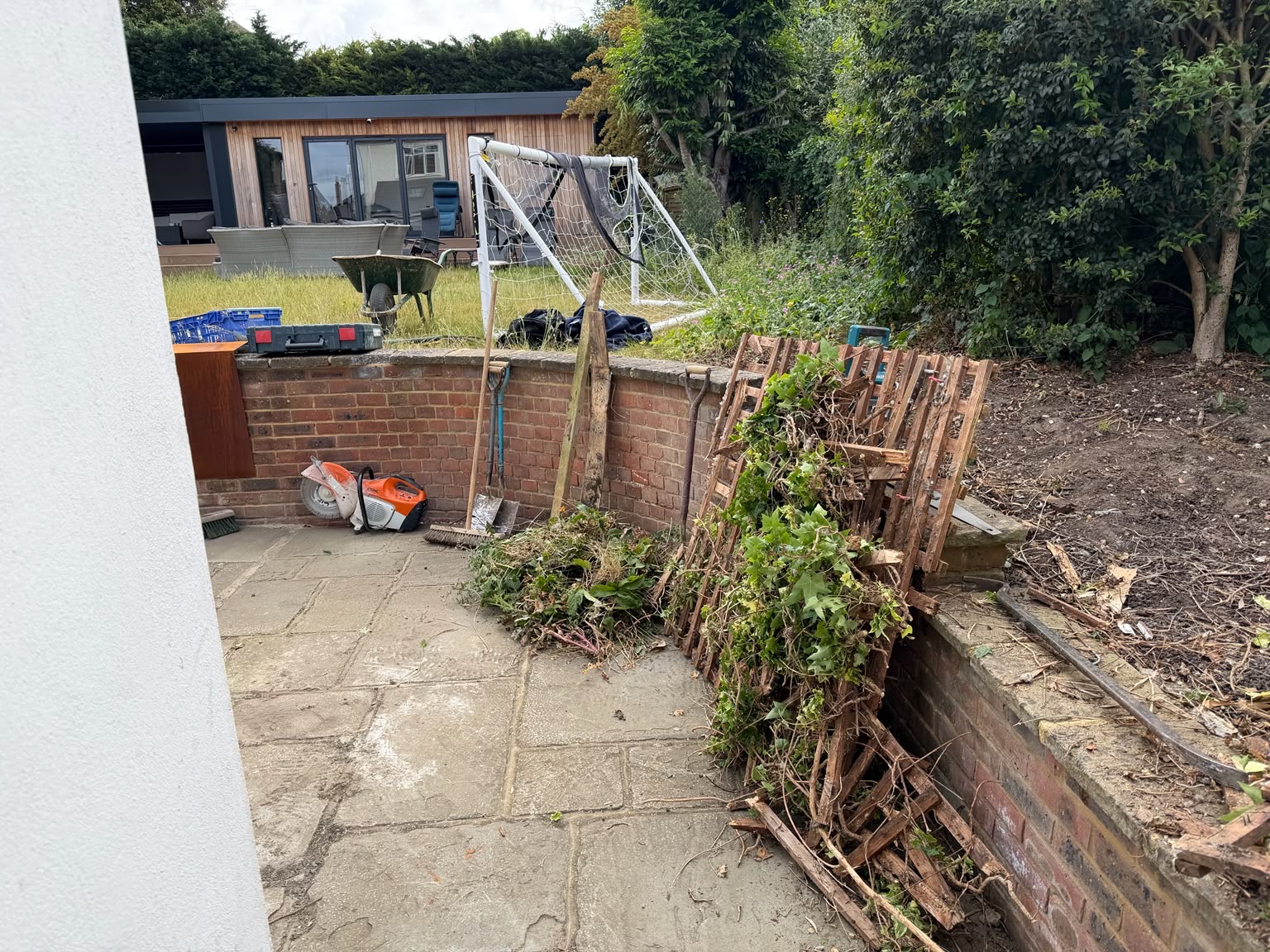 Site clearance underway, with old trellis and planting removed beside the brick retaining wall