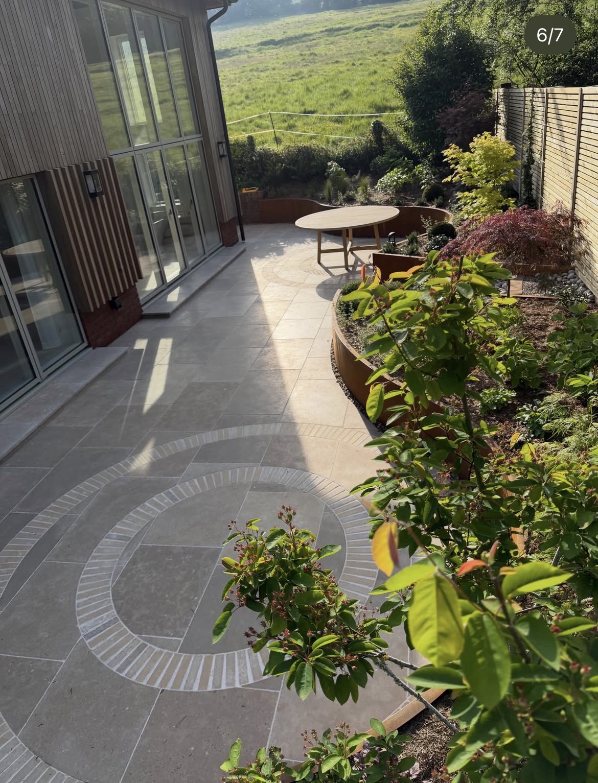 Completed garden terrace with circular paving detail, curved corten beds and countryside views