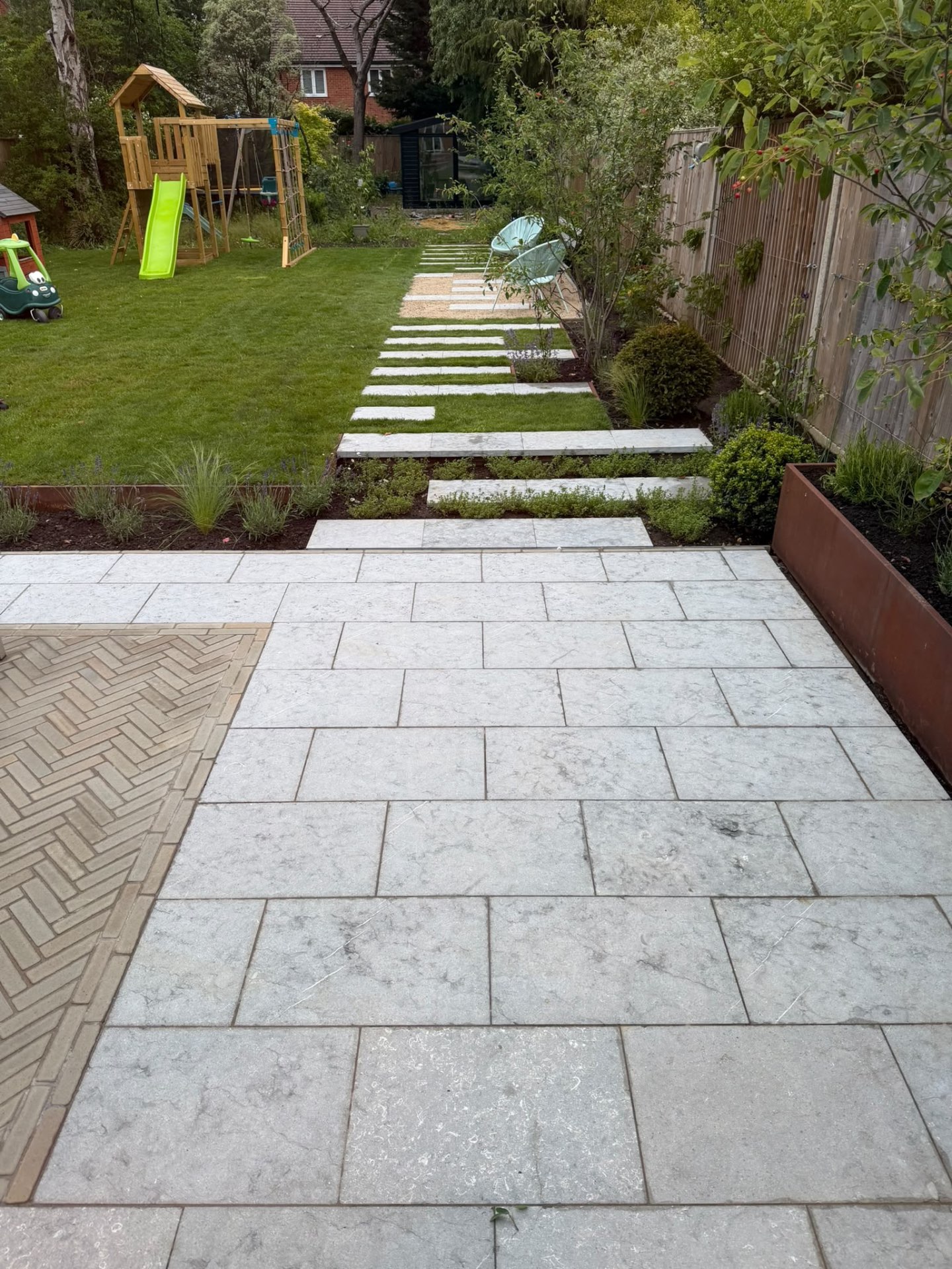 Limestone stepping stones crossing the lawn towards a gravel seating area