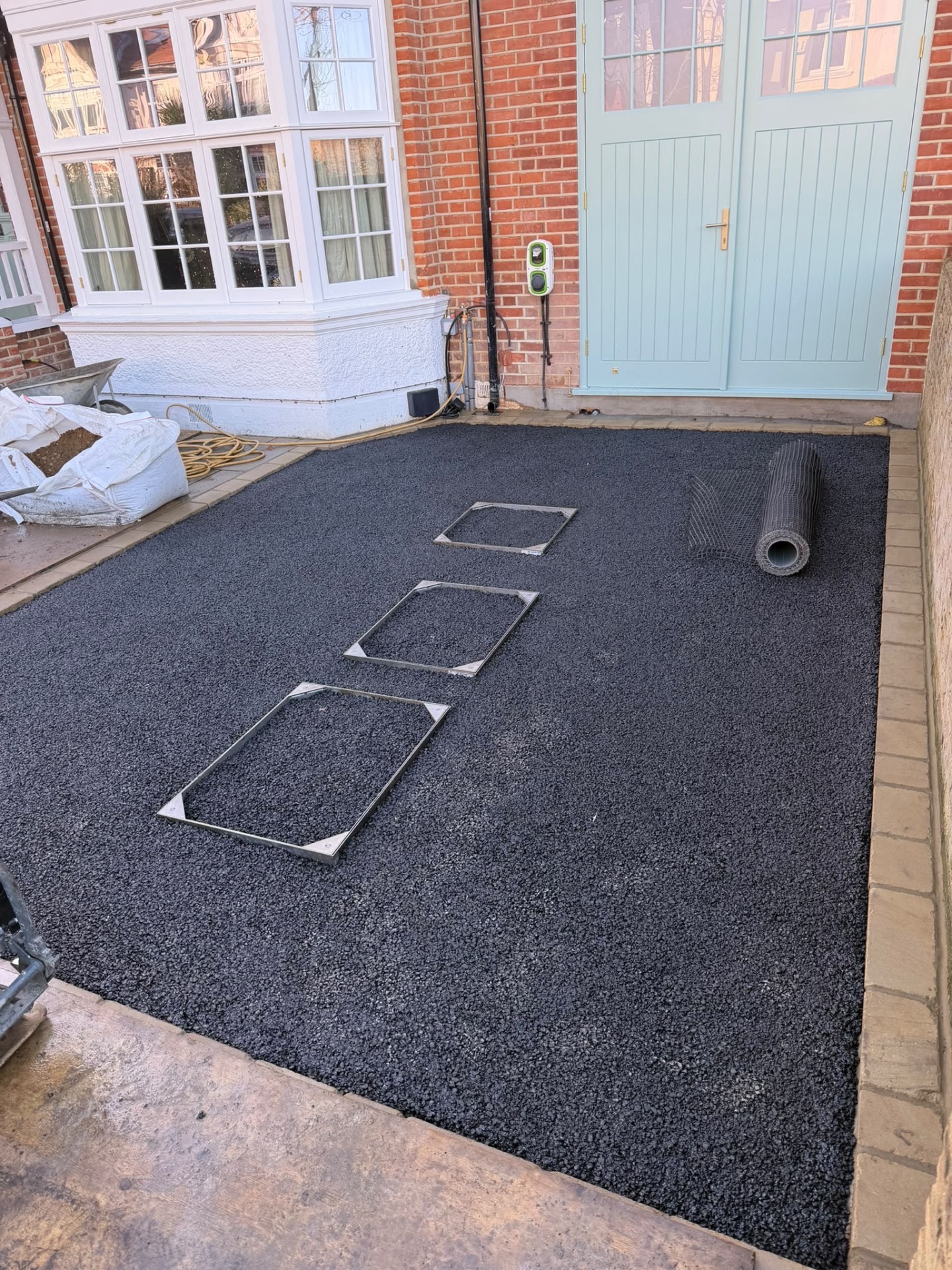Dark base layer spread across the driveway area over recessed utility frames
