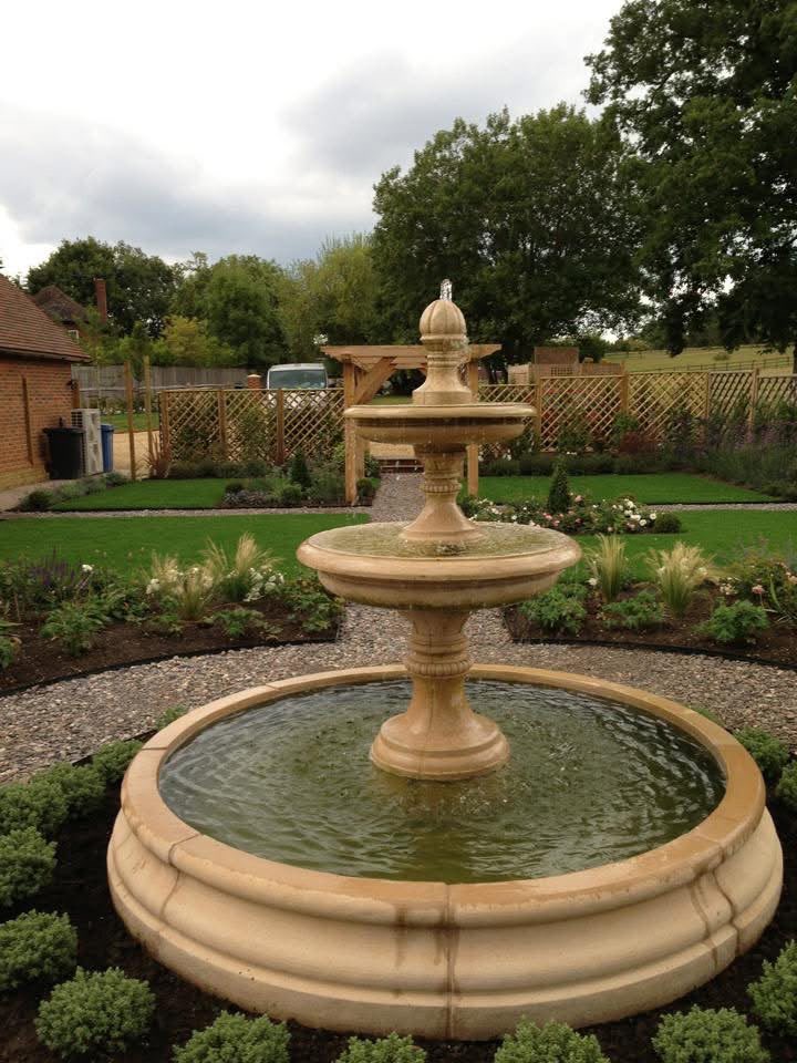 Tiered stone water feature surrounded by lawns, gravel paths and planting