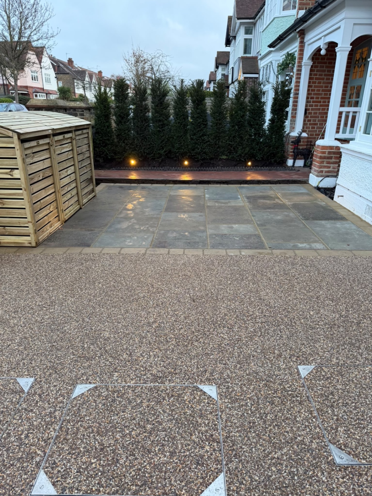 Yorkstone paving and resin-bound drive lit at dusk, with flush utility covers set into the resin
