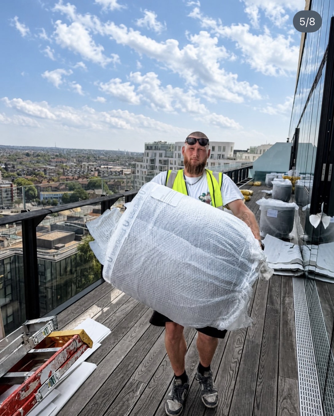 Landscape installer carrying a wrapped rooftop planter into position