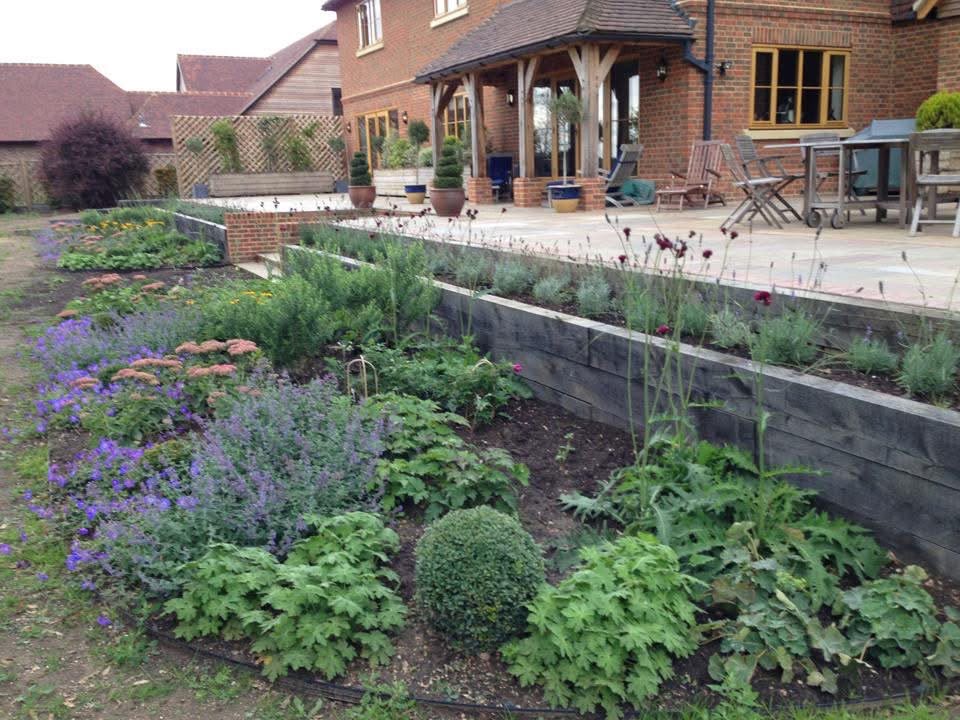 Layered flower beds beside the house and paved terrace